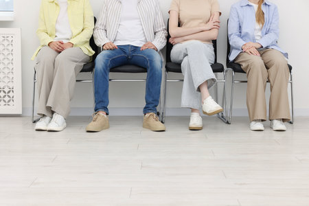 People waiting in queue on chairs indoors, closeupの写真素材