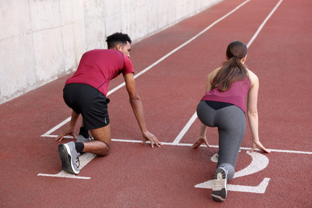 Couple in starting position for run at stadium, back view