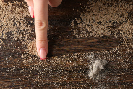 Woman swiping dust from wooden table, top view