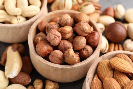 Mix of different nuts in bowls on table, closeup
