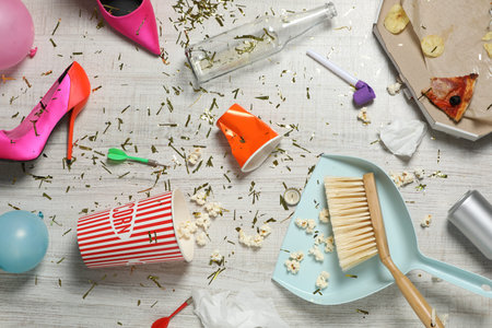 Brush and dustpan on messy floor after party, flat lay