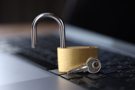 Cyber safety. Metal padlock and key on laptop, closeup