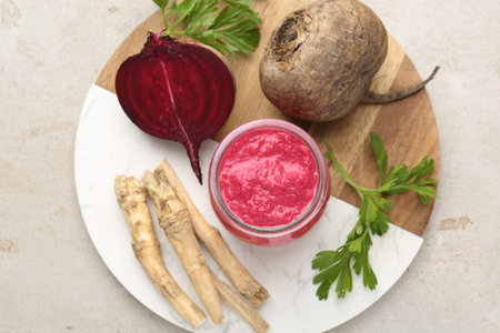 Tasty horseradish sauce with beetroot, parsley, roots and vegetables on light table, top view