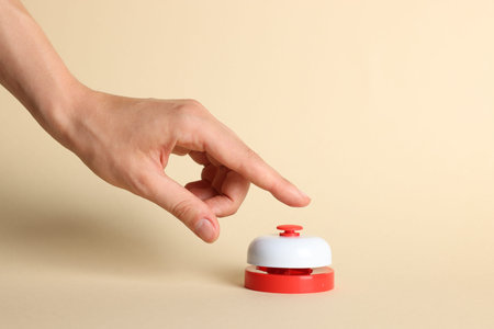 Woman pressing red button on beige background, closeup