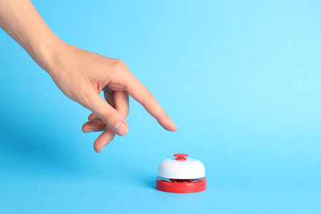 Person pressing red button on light blue background, closeup