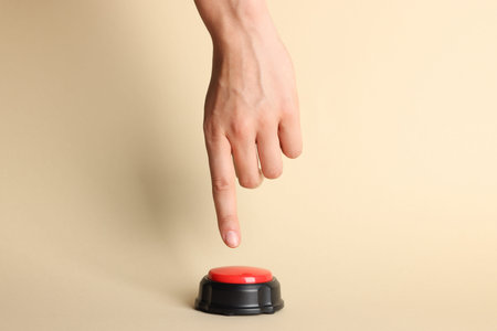 Woman pressing red button on beige background, closeup