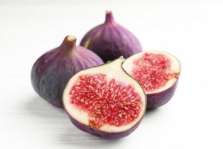 Whole and cut figs on white table, closeup