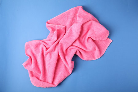 Pink terry towel on blue background, top view
