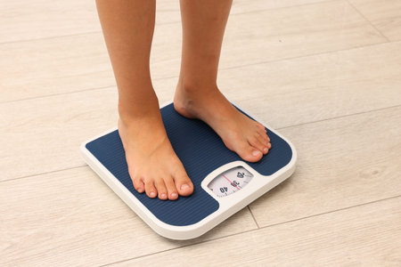 Little boy standing on scales indoors, closeup