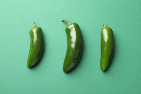 Ripe jalapeno peppers on green background, flat lay