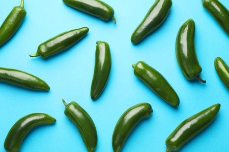 Green jalapeno peppers on light blue background, flat lay