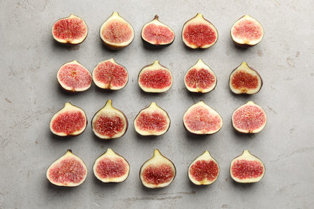Pieces of ripe figs on gray textured table, flat lay