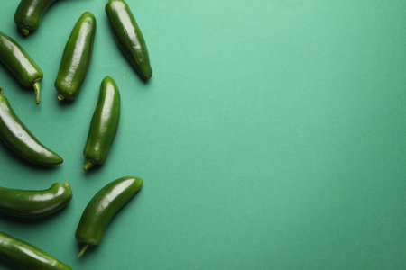 Ripe jalapeno peppers on green background, flat lay. Space for textの写真素材