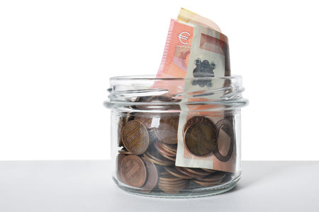 Glass jar with money isolated on white
