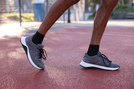 Man in sneakers running at stadium, closeup