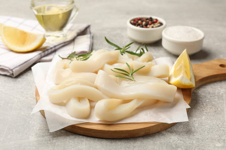 Uncooked squid rings and spices on gray table, closeup