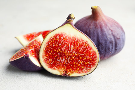 Whole and cut figs on gray table, closeup