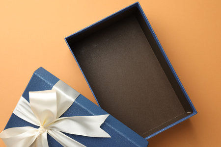 Open gift box with beautiful lid on orange background, top view