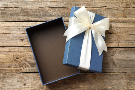 Opened gift box with beautiful lid on wooden table, top view
