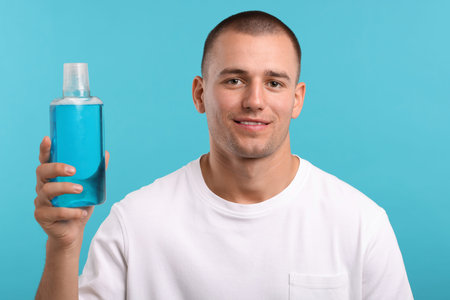 Man with bottle of mouthwash on blue backgroundの写真素材