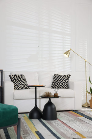 Stylish living room with lamp, tables and sofa. Interior design