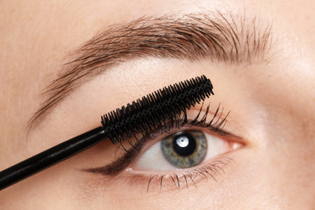 Woman applying mascara onto her eyelashes, closeup