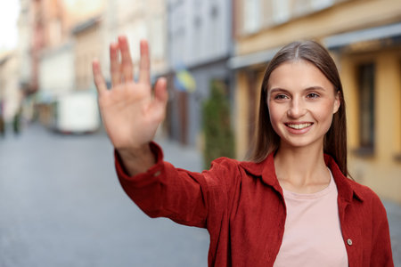 Goodbye. Happy woman waving on city streetの写真素材