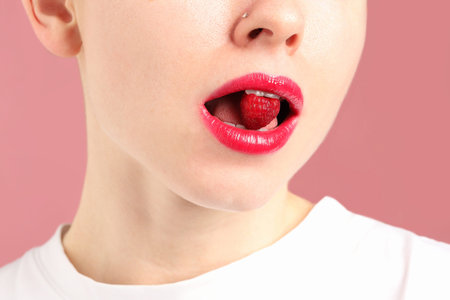 Woman with lips makeup and raspberry on pink background, closeup