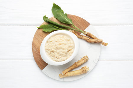 Tasty horseradish sauce and roots on white wooden table, top viewの写真素材