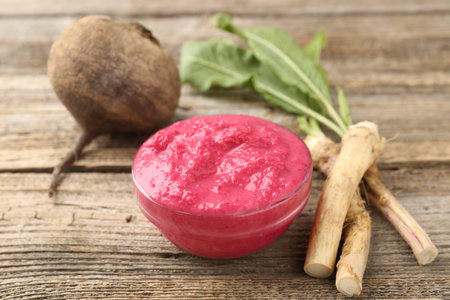 Tasty horseradish sauce with beetroot, roots and vegetables on wooden table, closeupの写真素材