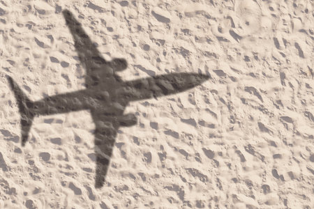 Flying airplane casting shadow on sand, top viewの写真素材