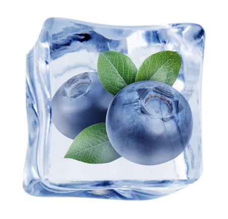 Ripe blueberries and green leaves in ice cube against white background