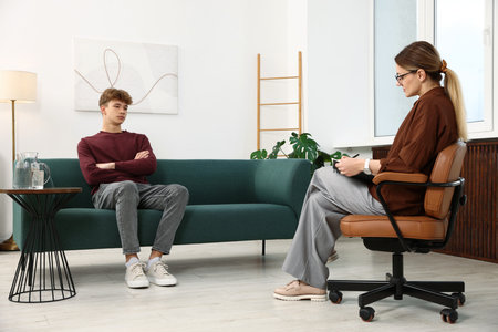 Professional psychologist working with teenage boy in officeの写真素材