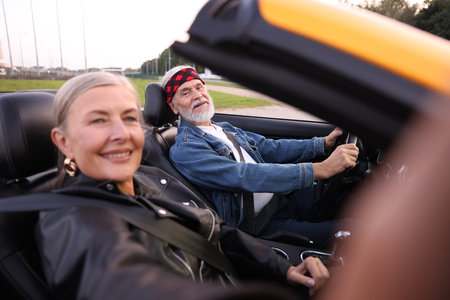 Senior woman taking selfie while man driving cabriolet outdoors, selective focusの写真素材