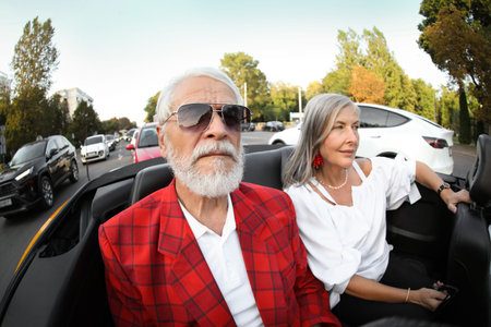 Senior couple enjoying cabriolet ride in city, wide angle lens