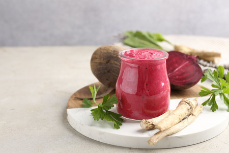 Tasty horseradish sauce with beetroot, parsley, roots and vegetables on light table, closeup. Space...