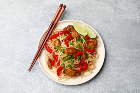 Tasty noodles with chicken, green onions and vegetables served on light gray table, top viewの写真素材