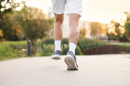 Athletic man in sneakers running outdoors, closeup