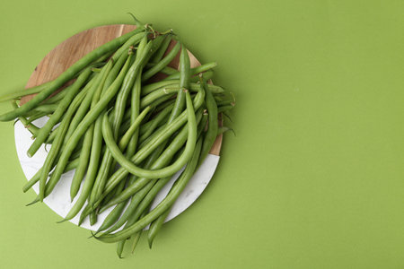Fresh bean pods on green background, top view. Space for text