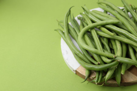 Fresh bean pods on green background, closeup. Space for text