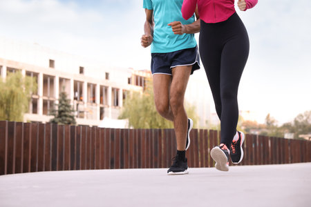 Couple in sportswear running outdoors, closeup. Space for text