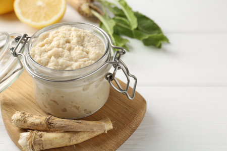 Tasty horseradish sauce, roots and lemons on white wooden table, closeup. Space for textの写真素材