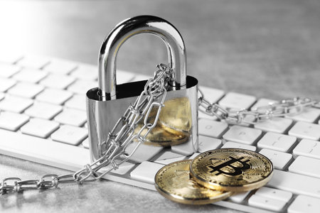 Cyber safety. Metal padlock, chain, bitcoins and computer keyboard on gray table, closeup