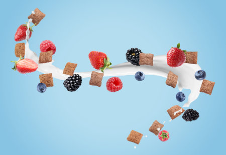 Splashing milk with fresh berries in air against light blue background. Healthy breakfast