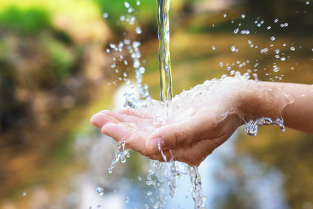 Save water concept. Woman holding her hand under flowing clean water near river outdoors, closeup