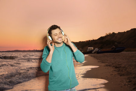 Happy man listening to sounds of nature which making him feel calm. Beautiful seascape on backgroundの写真素材