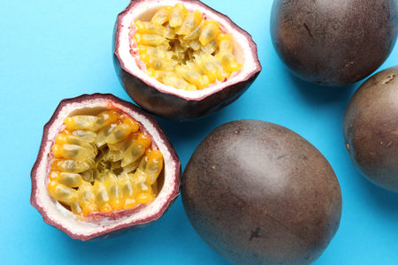 Fresh passion fruits on light blue background, closeup. Whole and cut