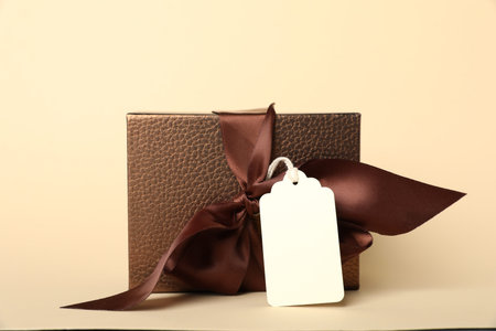 Gift box with blank tag on beige background