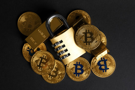 Bitcoins, padlock and gold bars on black background, top view