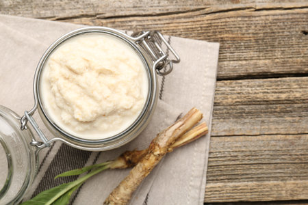 Tasty horseradish sauce and roots on wooden table, flat lay. Space for textの写真素材